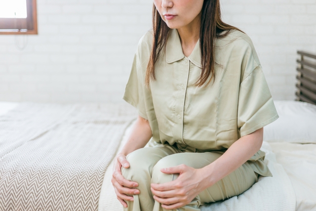 起床時に起こる辛い膝の痛みに悩む女性